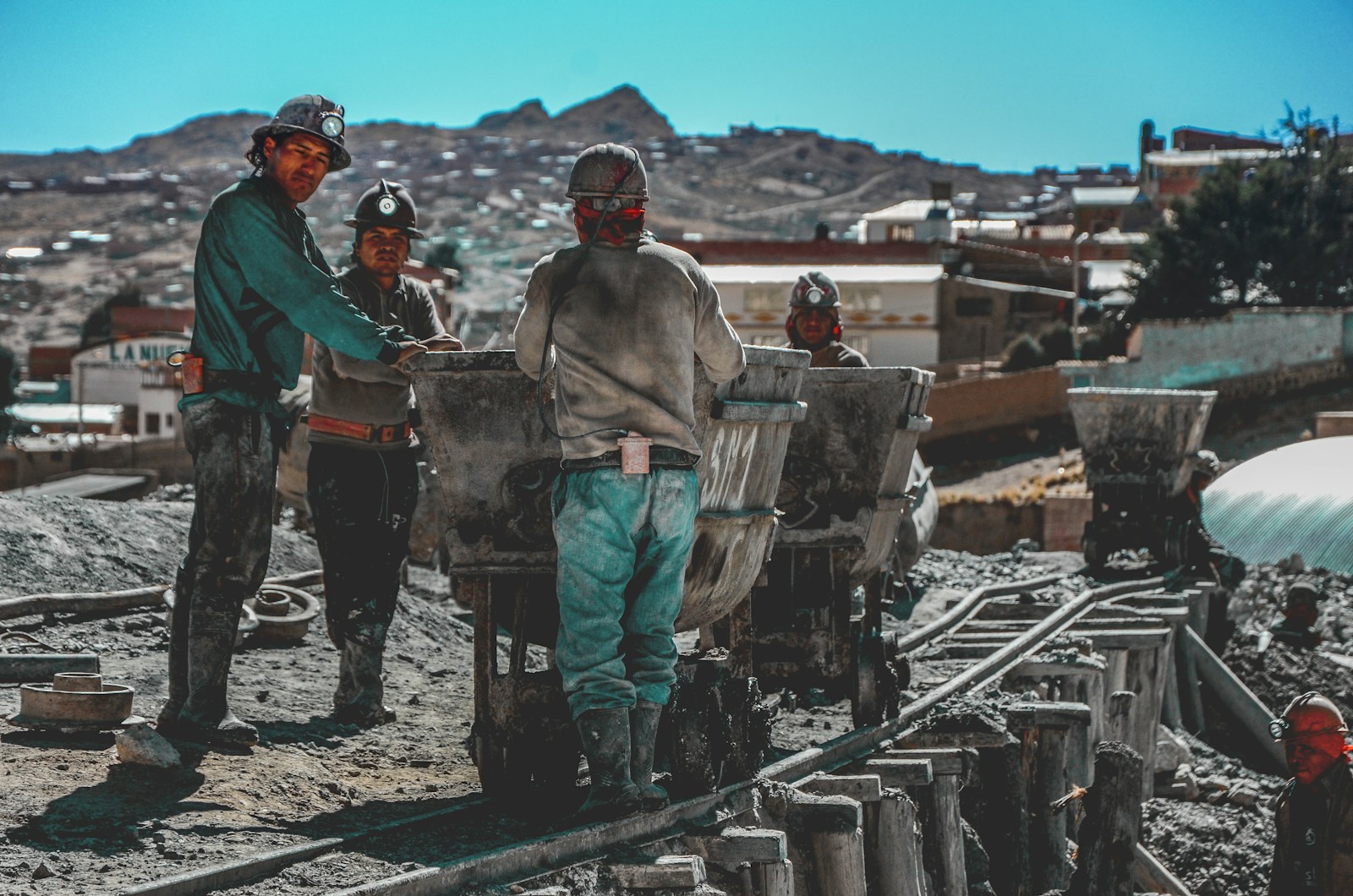 construction workers standing near wheelbarrows near mountain